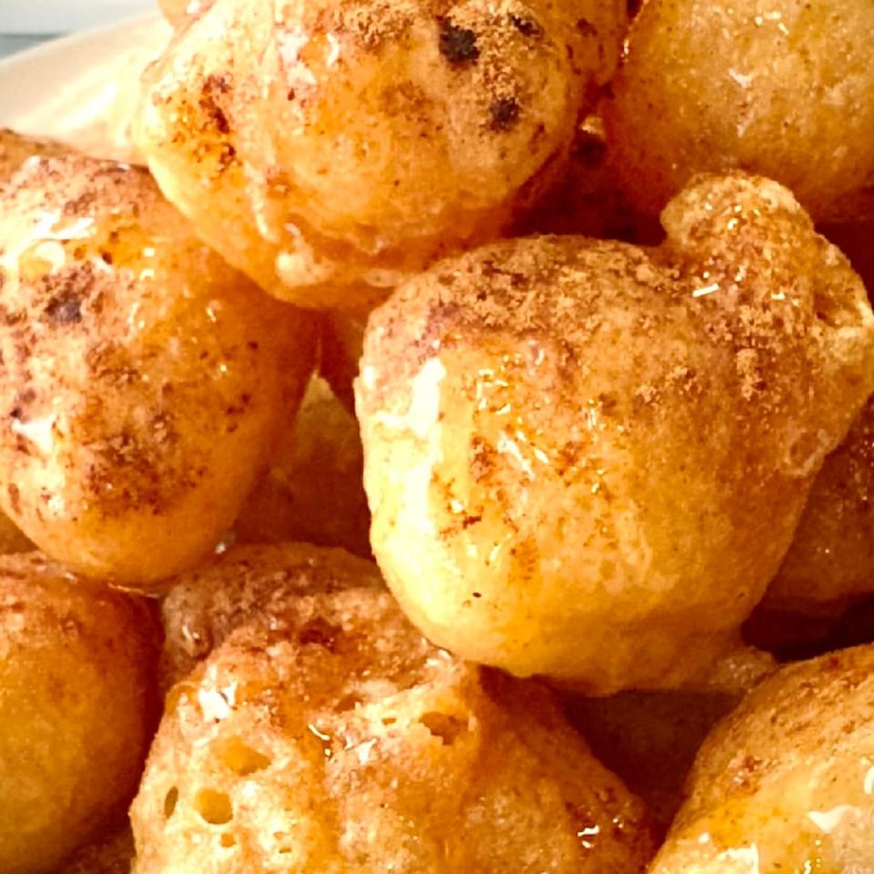 Close-up of golden-brown Greek Loukoumades, drizzled with honey and sprinkled with cinnamon.