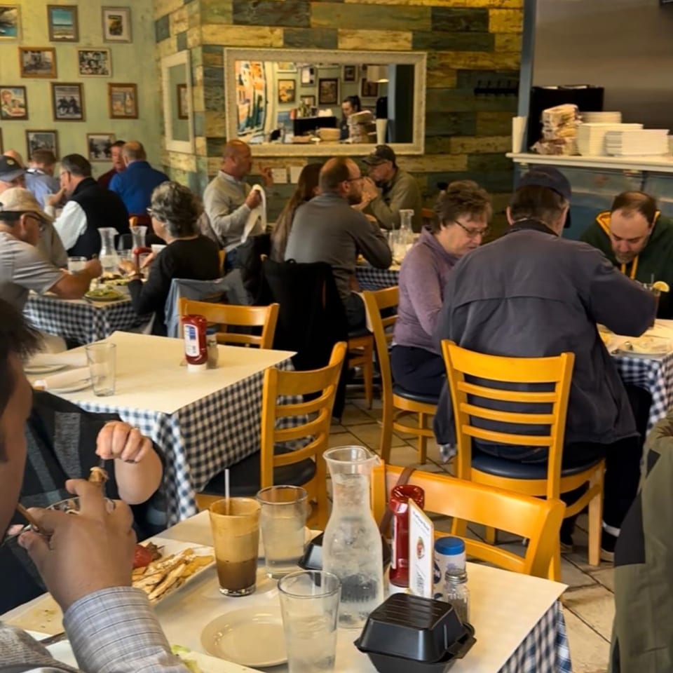 Diners enjoying meals at tables with blue and white checkered tablecloths inside Gyro House.